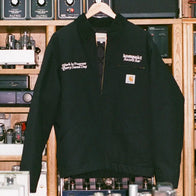 Carhartt WIP Kompakt Record Bar Jacket Jacket unisex detail view 3 | Dash Racegear — Front of a black Carhartt WIP x Kompakt Record Bar jacket hanging in a studio