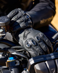 Alpinestars SP X 7 black perforated leather motorcycle gloves with TPU knuckle protection on motorcycle handlebars.