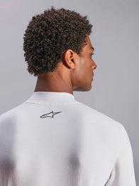 Alpinestars ZX Evo V3 Top, Long Sleeve Auto Racing Base Layer, White, close-up of back neck area featuring black Alpinestars logo, technical flame-resistant fabric, worn by model with dark curly hair
