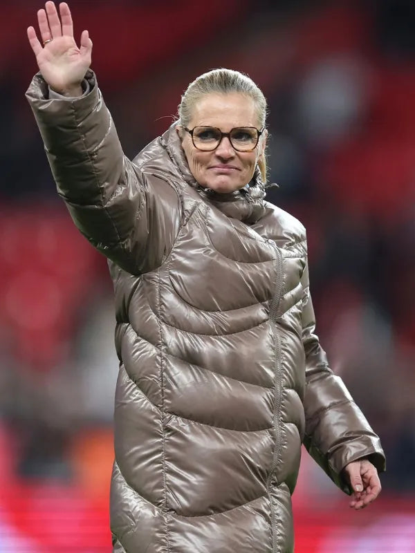 Sarina Wiegman Women’s International Friendly 2025 Puffer Coat Coat unisex front product view | Dash Racegear — England Manager Sarina Wiegman Women’s International Friendly 2025 Taupe Glossy Maxi Puffer Coat, curved quilting design for stylish winter…