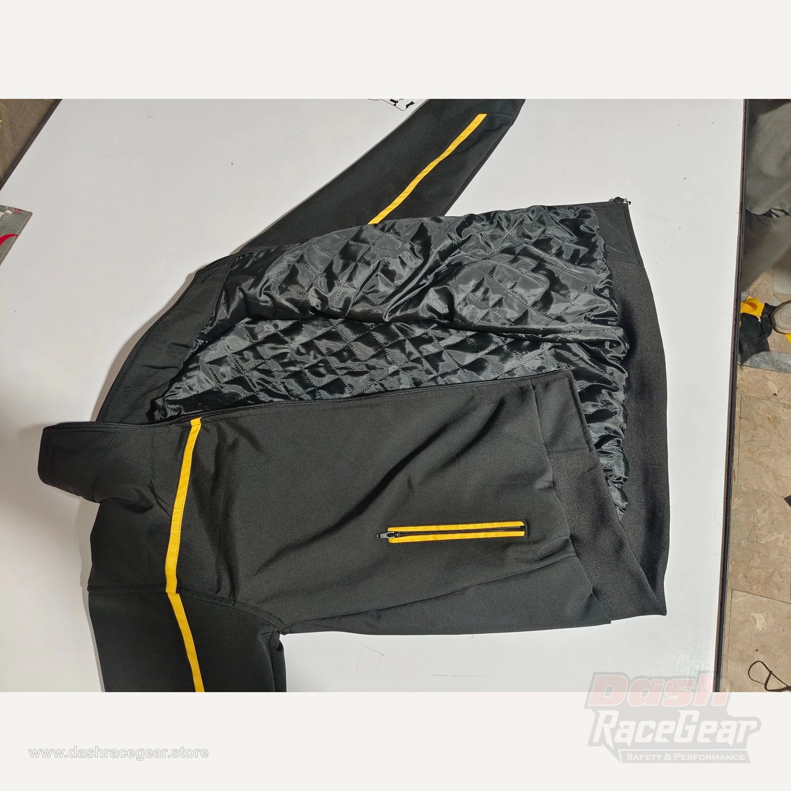 Apex black yellow softshell jacket flat lay with lining and sleeve piping visible