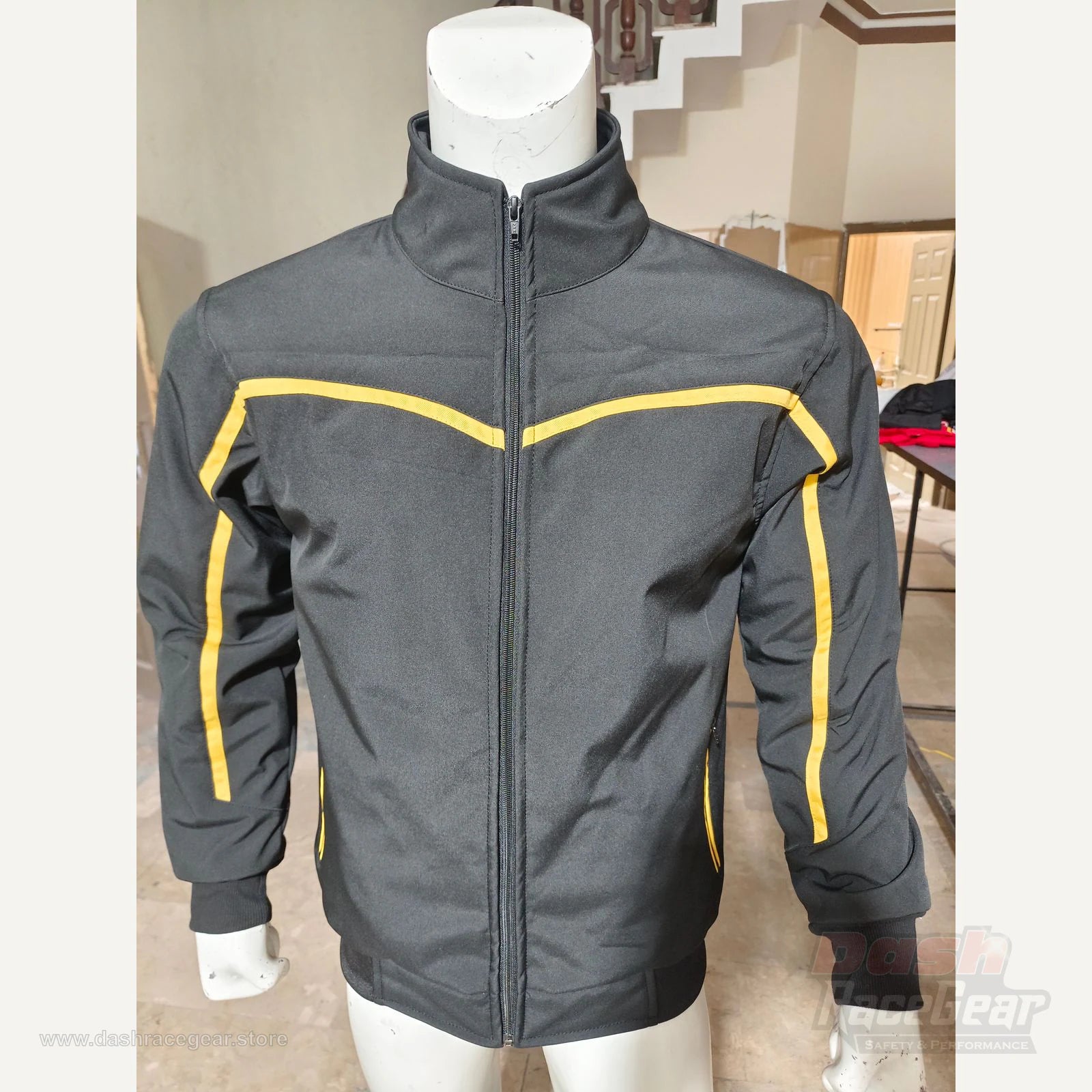Apex softshell jacket front detail showing black fabric and yellow chest piping