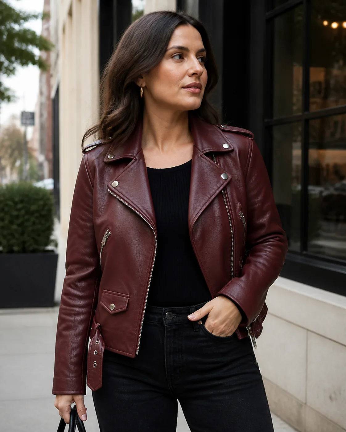Woman wearing a burgundy leather biker jacket on a modern city street